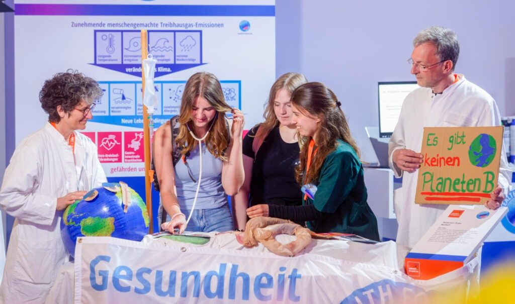 Schülerinnen stehen an einem Infostand und behandeln "Patientin Erde"
